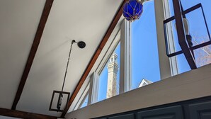 A kitchen with dark blue cabinets, a hanging light fixture, and a view of a tower through a window. - Be right in the action in our centrally-located 2BR/1BA condo with Hot Tub (Provincetown)
