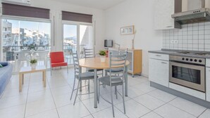 Een moderne keuken met een inbouwoven en een eethoek met een ronde tafel en stoelen.