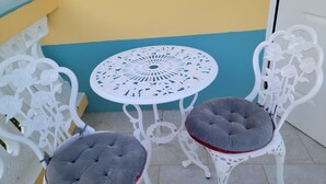 A white metal table with a floral design and two cushioned chairs with grey cushions. - Jane's Hideaway (Frederiksted)