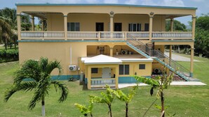A two-story building with a balcony, a staircase, and a small covered area. - Jane's Hideaway (Frederiksted)