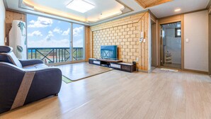 Un vaste espace de vie comprenant un grand téléviseur, un canapé et un balcon avec vue.