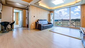 Une pièce spacieuse dotée d’un plancher en bois, d’un canapé et d’une grande fenêtre offrant une vue sur le ciel et le paysage.