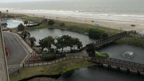 A view of a beach, a small lake, and a bridge connecting the two. There are picnic tables and chairs near the lake. - Beautiful view At Myrtle Beach Resort (Myrtle Beach)