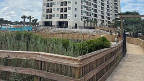 A tall, modern high-rise building with multiple balconies and a wooden boardwalk in the foreground. - Beautiful view At Myrtle Beach Resort (Myrtle Beach)