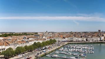 Un port de plaisance où sont amarrés des bateaux, entouré d’un paysage urbain avec des bâtiments historiques et un ciel dégagé.