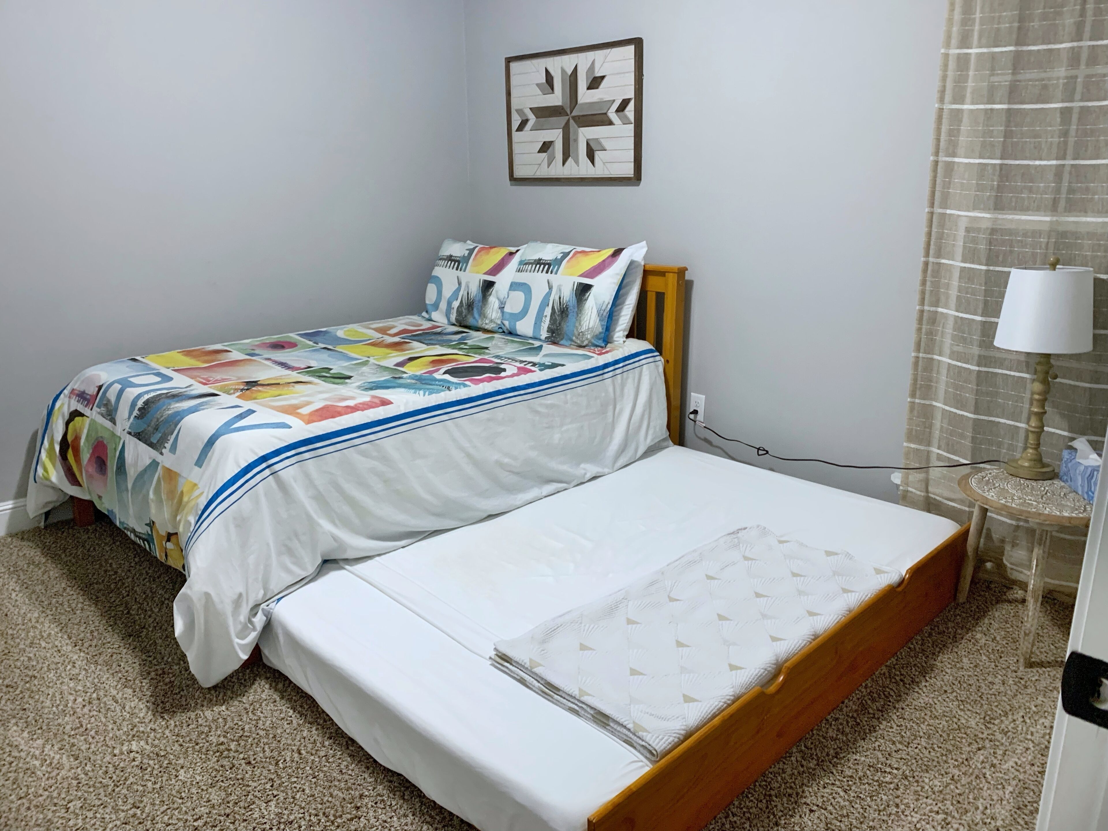 A bedroom with a bed, a bedside table with a lamp, and a wall-mounted picture.