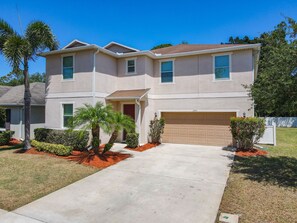 A two-story house with a garage, a front porch, and a well-maintained lawn.