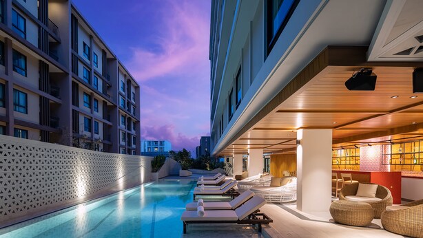 Área da piscina com espreguiçadeiras e bar.