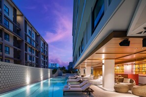 A poolside area with lounge chairs and a bar area. - Travelodge Phuket Town (Wichit)