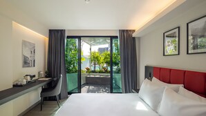 Quarto de hotel com cama, escrivaninha, cadeira e vista para o exterior.