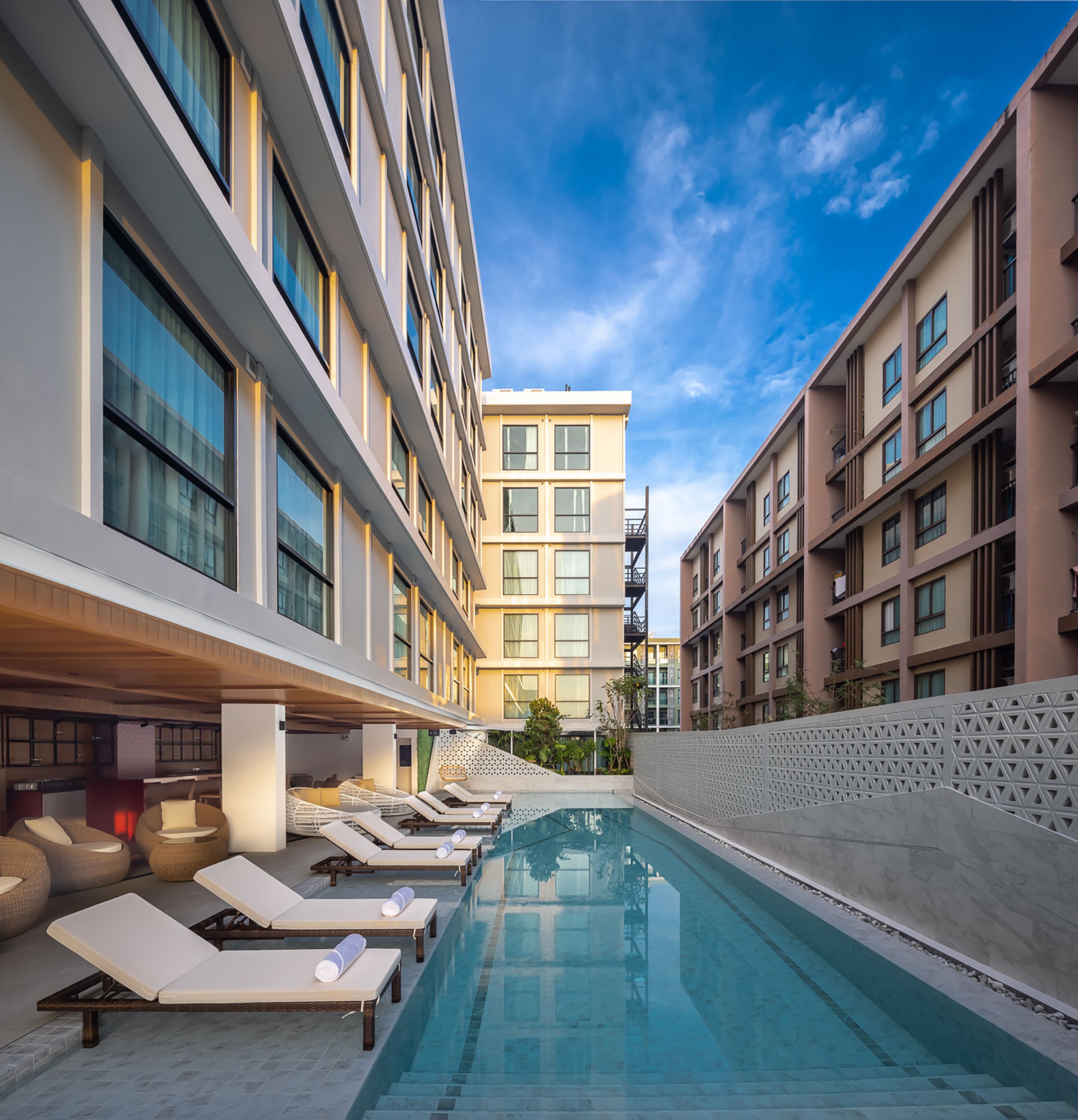 A modern hotel with a rooftop pool area, sun loungers, and a clear view of the sky.