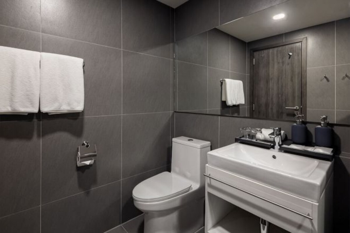 Un baño moderno con inodoro, lavabo y espejo.