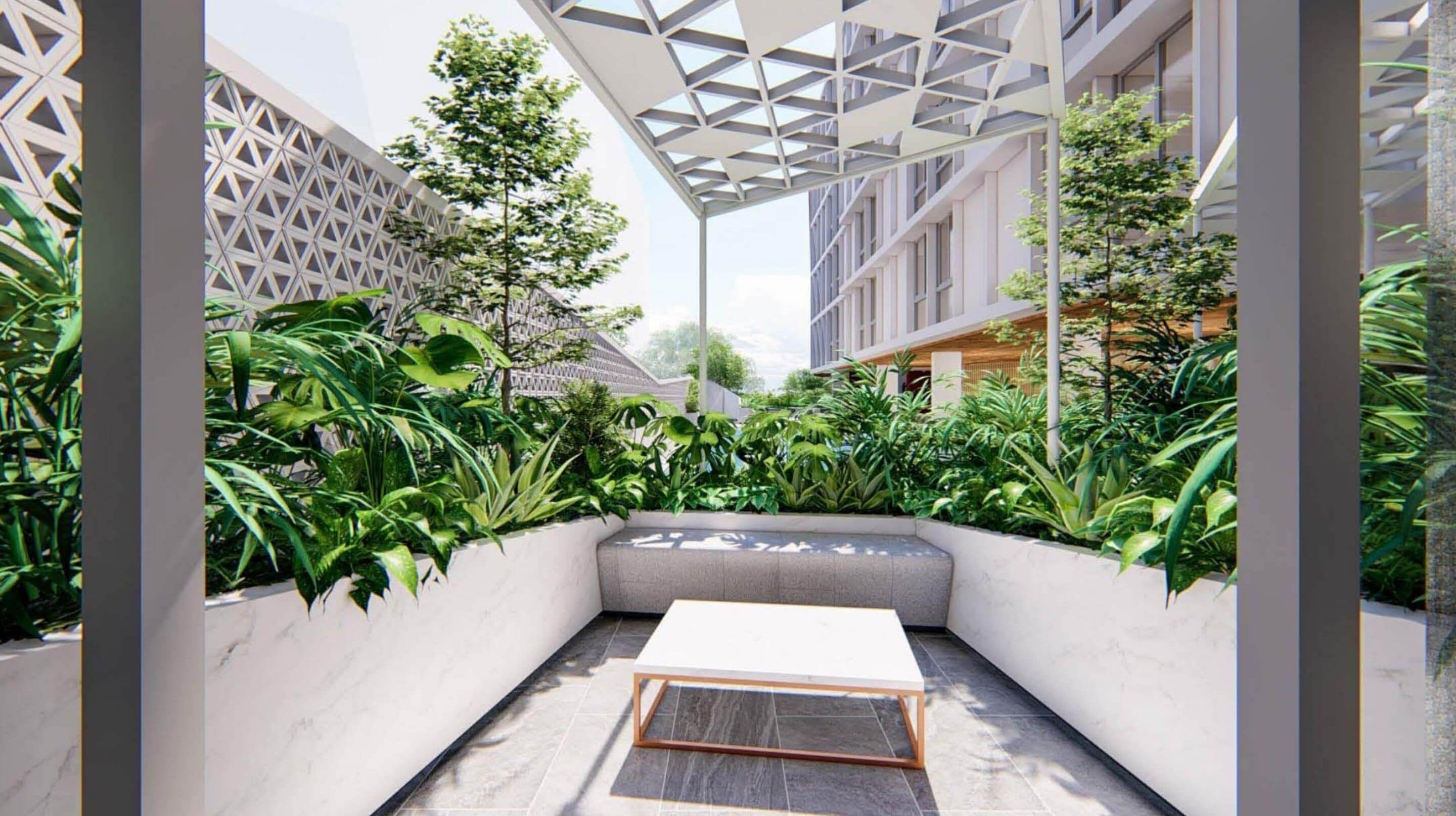 A modern outdoor seating area with a white bench and a small table, surrounded by lush greenery and a geometric metal structure overhead.