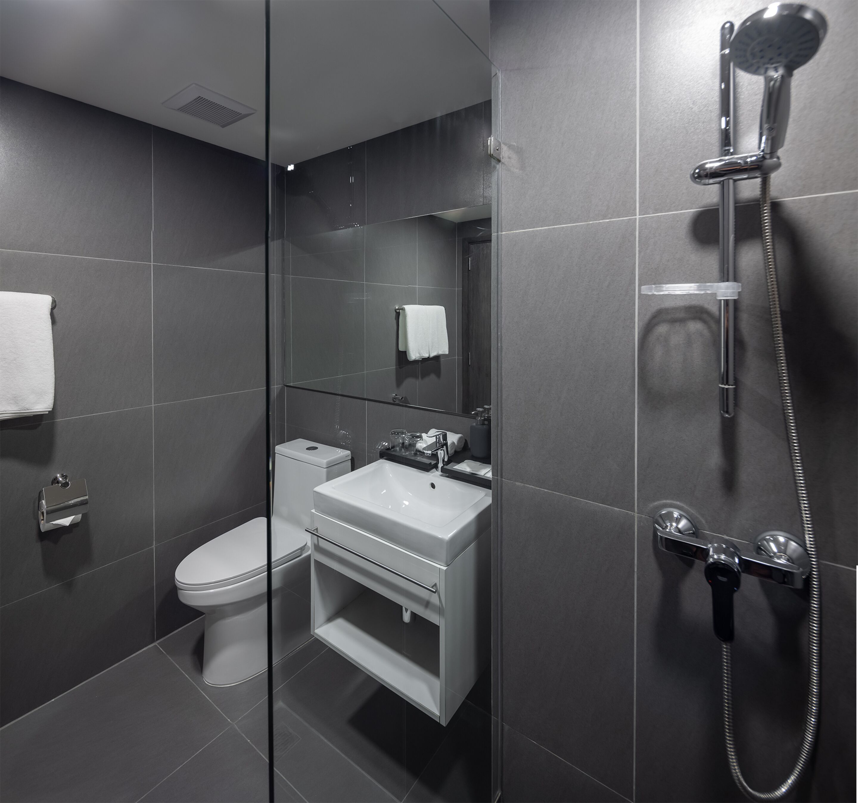 Un baño moderno con ducha envuelta en vidrio, inodoro y lavamanos.
