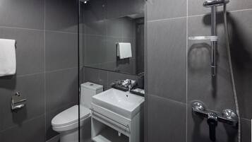 Un baño moderno con ducha envuelta en vidrio, inodoro y lavamanos.