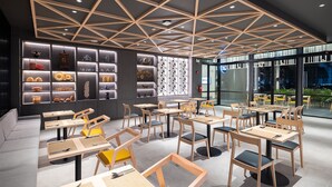 Interior de restaurante moderno com design geométrico no teto, mesas e cadeiras de madeira e estantes exibindo diversos objetos.