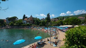 Une zone de baignade en bord de mer équipée d’une plateforme de plongeon, de chaises longues et de parasols.