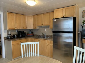 A kitchen with wooden cabinets, a stainless steel refrigerator, a coffee maker, and a toaster.