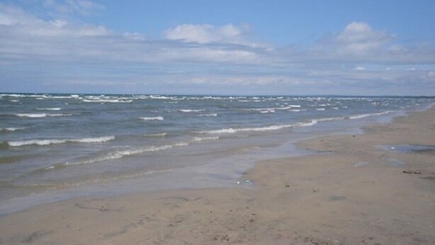 Ein Strand mit Wellen und blauem Himmel.