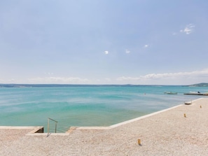 Una spiaggia con vista libera sul mare, una zona sabbiosa e alcune barche in acqua.