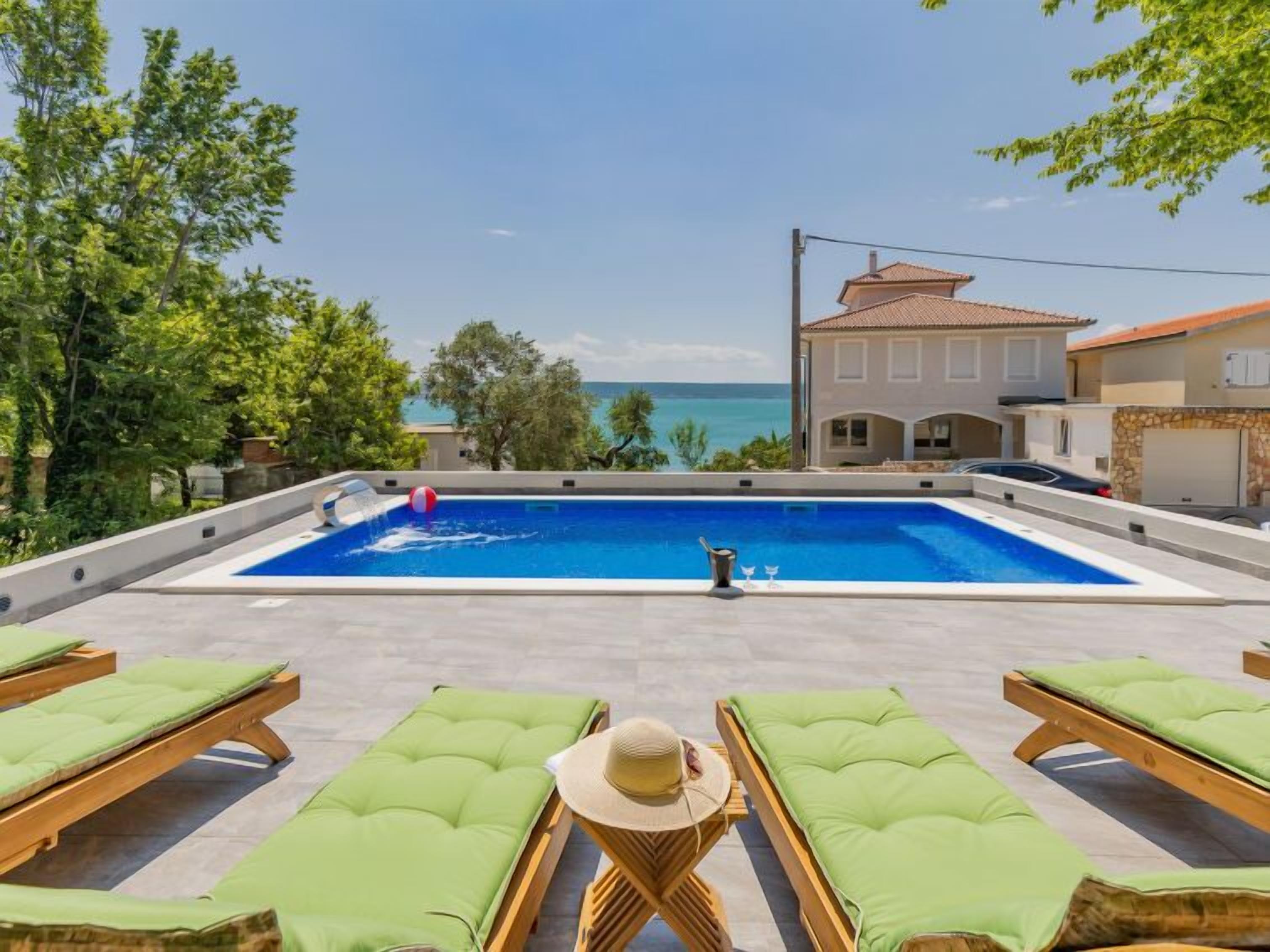 A pool with lounge chairs and a view of the sea.