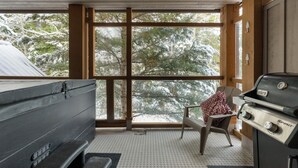 Un intérieur de chalet chaleureux avec une grande fenêtre, un barbecue et un banc.