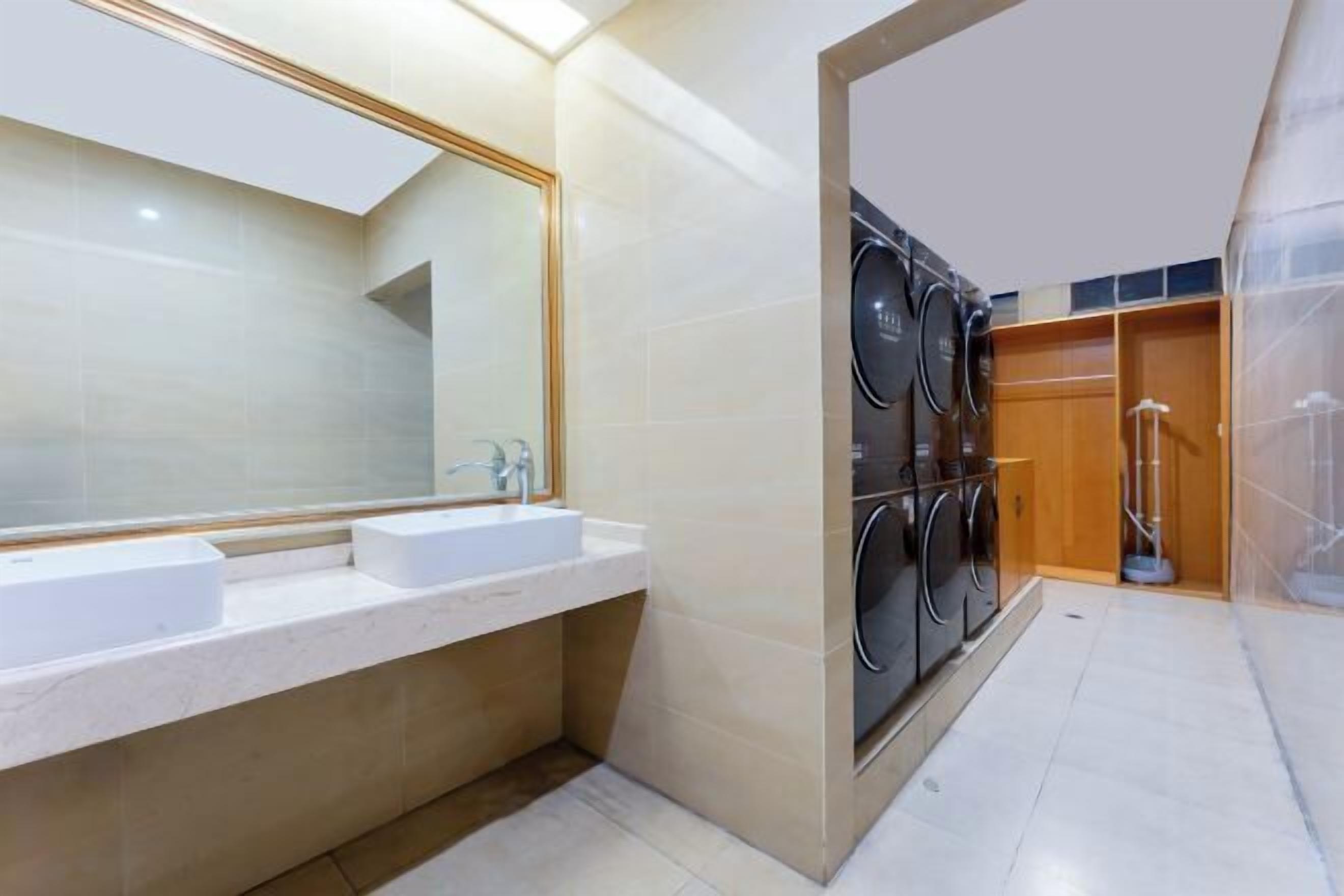 A modern bathroom with dual sinks, a large mirror, and a built-in laundry machine.
