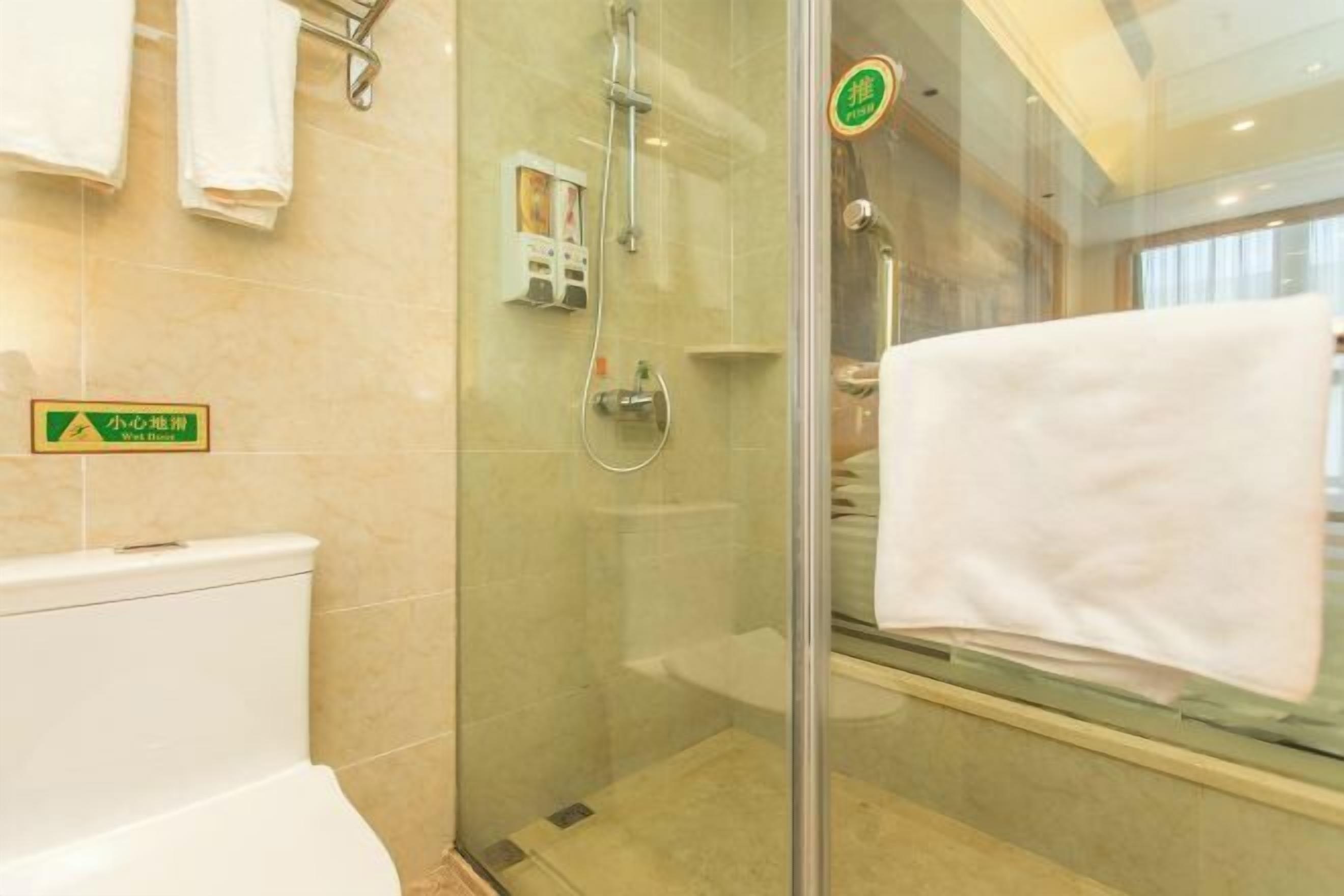 Een moderne badkamer met een douchecabine van glas, een toilet en een wastafel.