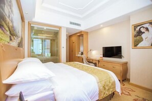 A hotel room with a bed, a desk, a television, and a painting on the wall.