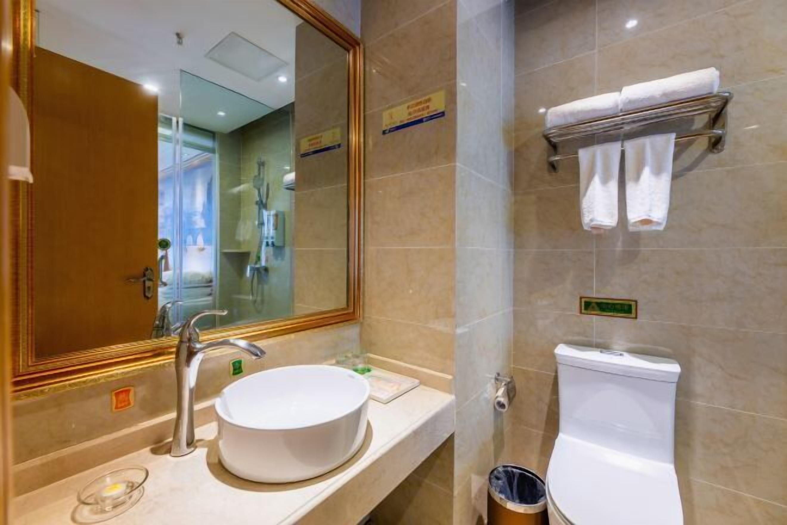 Un bany amb un lavabo, mirall, vàter i paraigua per a tovalloles.