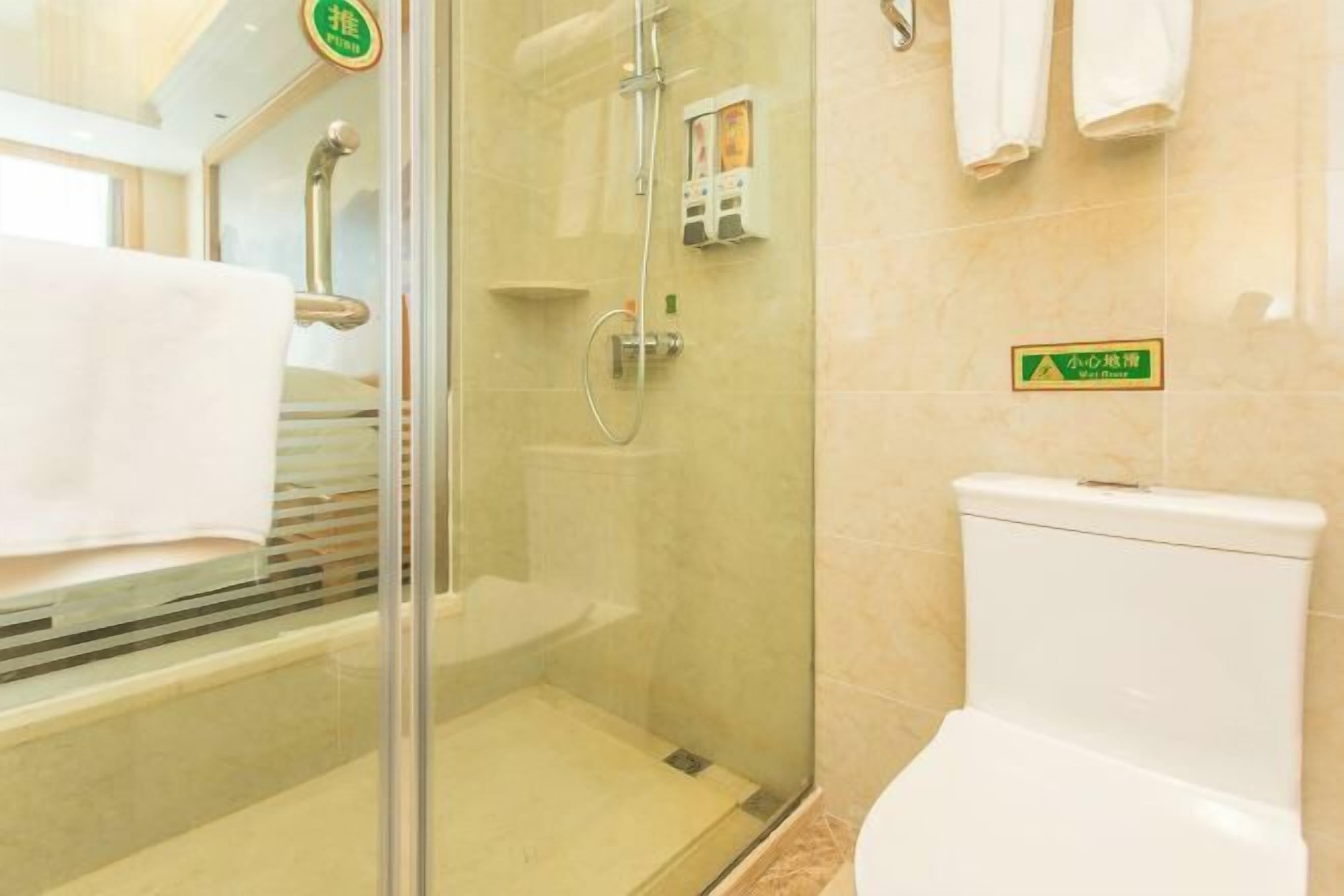 A bathroom with a glass-enclosed shower, a toilet, and a towel rack.