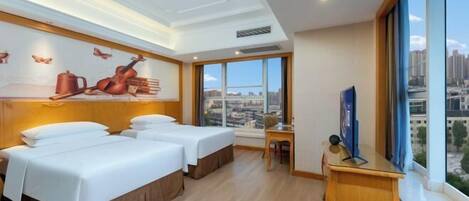 A hotel room with two beds, a desk, a chair, and a TV.