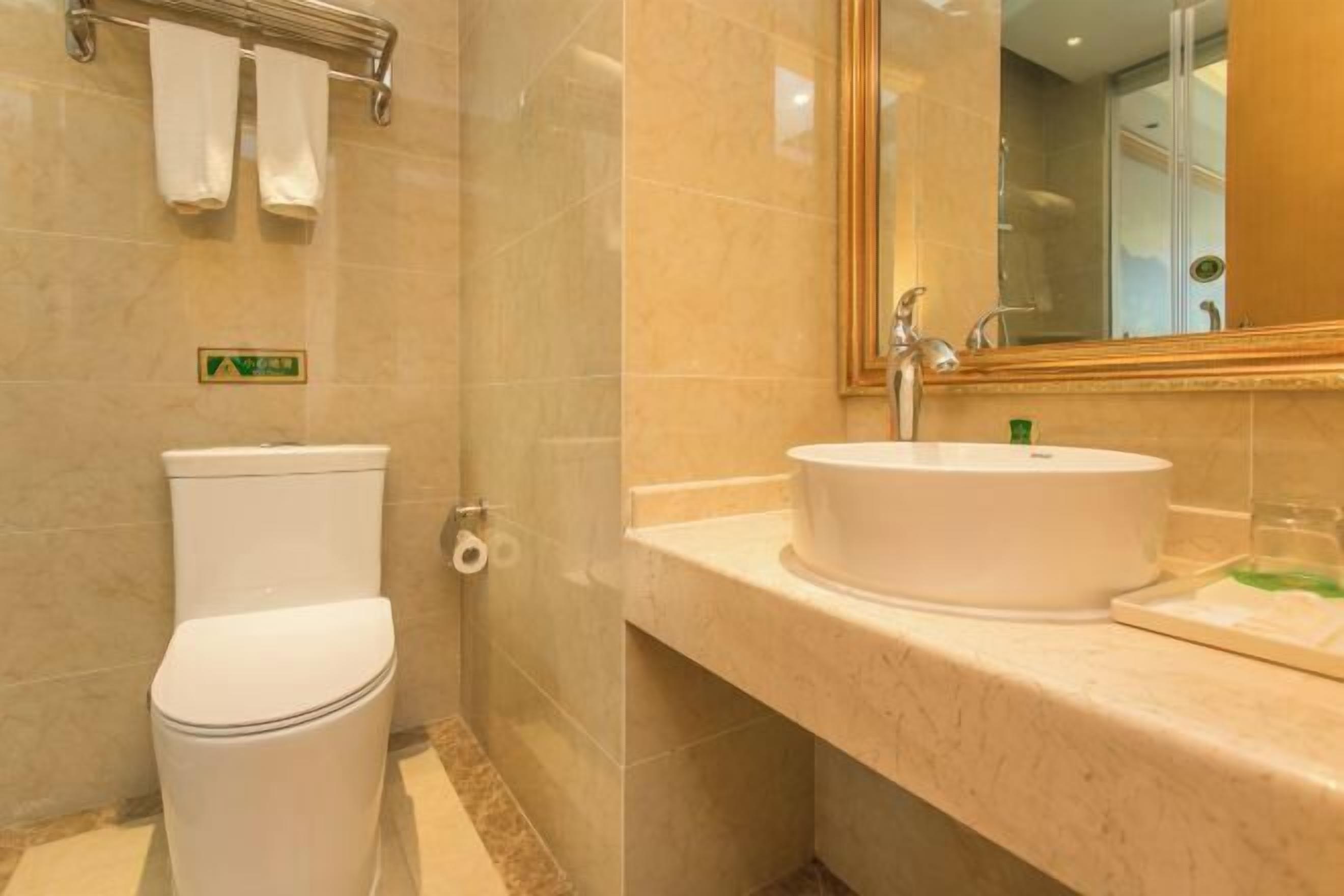 Une salle de bain comprenant des toilettes, un lavabo avec un miroir et un porte-serviettes.