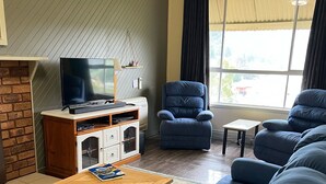 A living room with a sofa set, a television, a small table, and a fireplace.