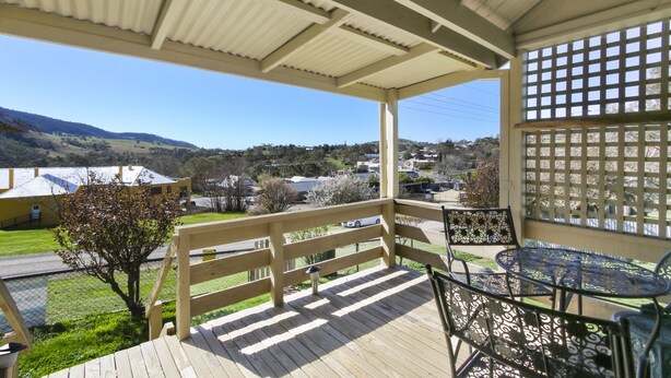 A covered outdoor area with a wooden deck, metal chairs, and a table.