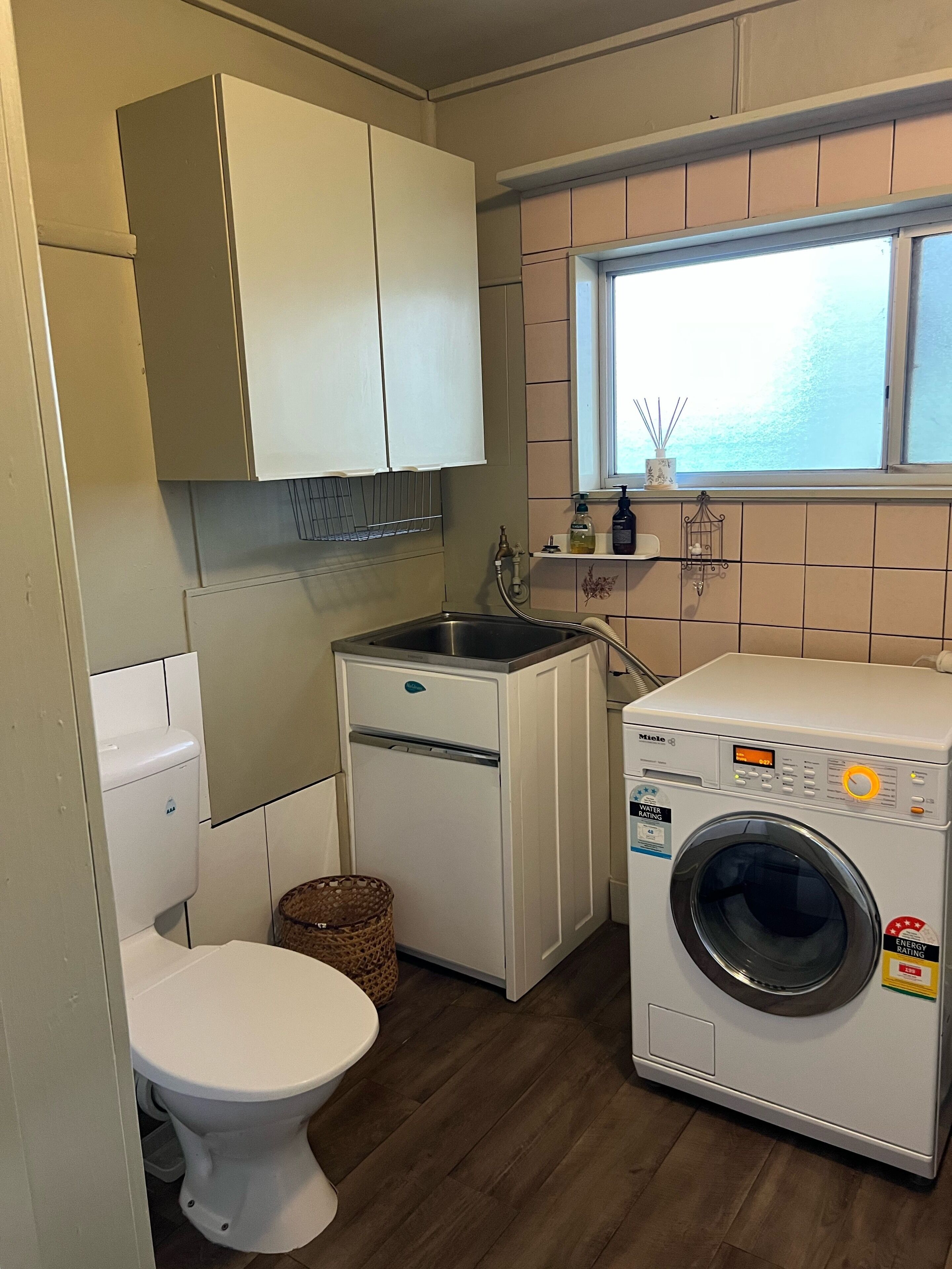 Ein kleiner Hauswirtschaftsraum mit Waschmaschine, Spüle und Toilette.
