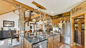 Una cocina con una isla grande, armarios de madera, un refrigerador de acero inoxidable y un letrero que dice 'Pantry'.