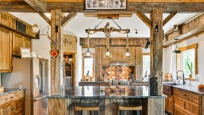 Una cocina amplia con armarios de madera, una isla grande con taburetes de bar y una lámpara colgante.