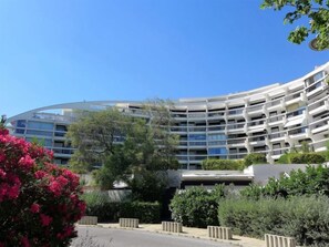 Un hôtel moderne à plusieurs étages, doté d’une façade incurvée, de balcons et d’un aménagement paysager luxuriant.