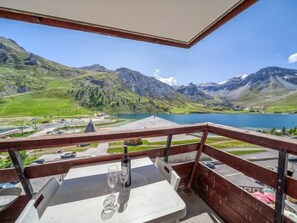 A balcony with a table, two wine glasses, and a bottle, overlooking a lake and mountains. - Palafour (Le Lac) by Interhome (Tignes)