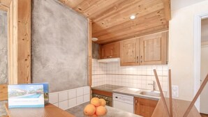 A modern kitchen with wooden cabinets, a tiled backsplash, and a wooden countertop. - Palafour (Le Lac) by Interhome (Tignes)