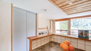 A modern kitchen with a wooden countertop, a bowl of oranges, and a view of a mountain landscape through the window. - Palafour (Le Lac) by Interhome (Tignes)