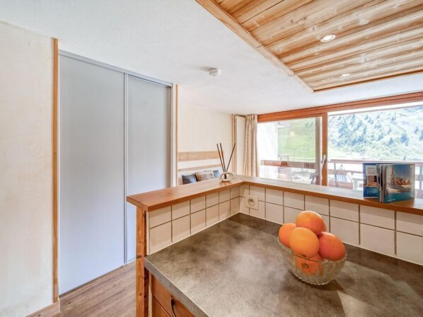 A modern kitchen with a wooden countertop, a bowl of oranges, and a view of a mountain landscape through the window. - Palafour (Le Lac) by Interhome (Tignes)