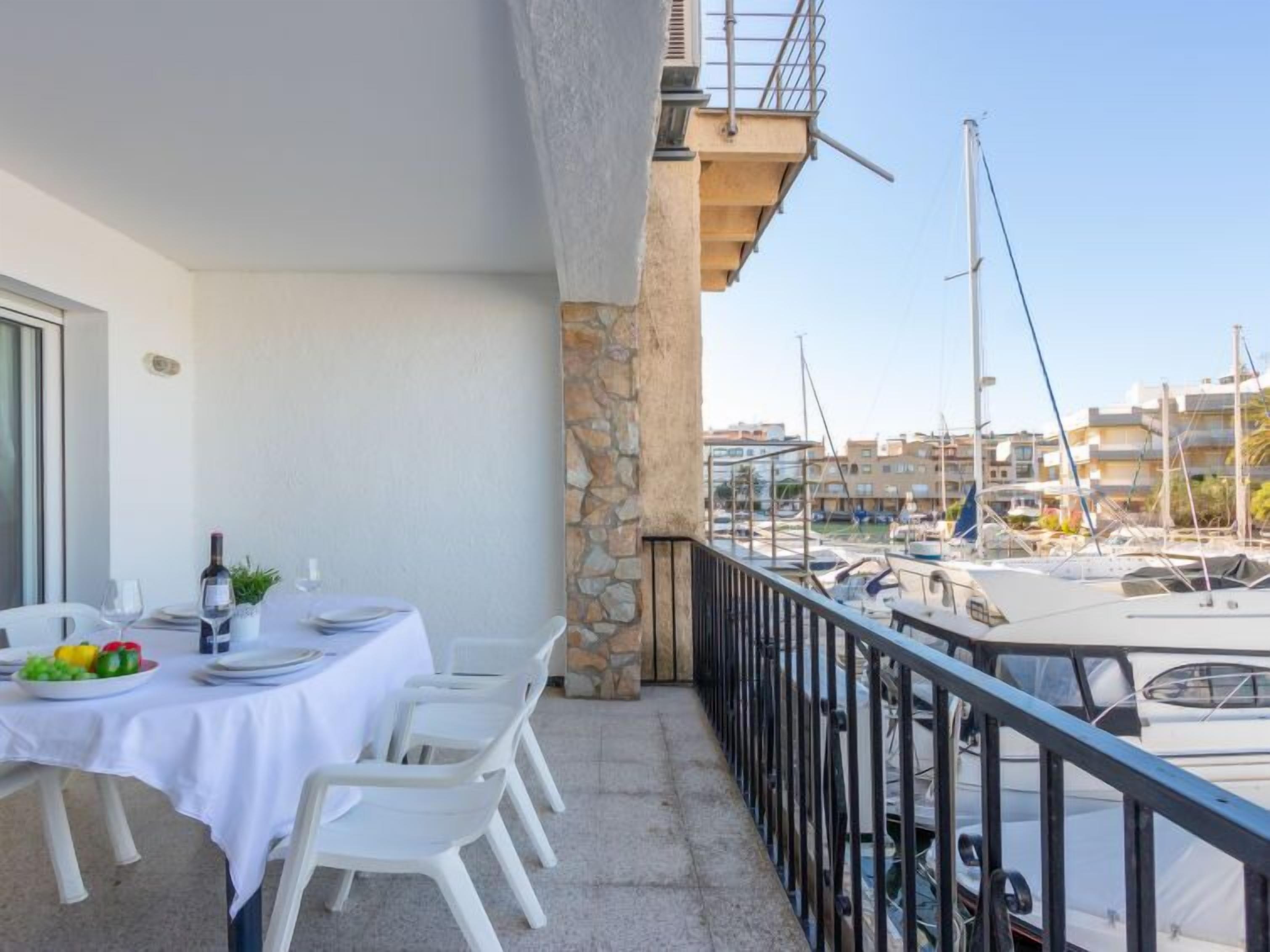 A balcony with a table set for dining, overlooking a marina with boats.