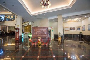 A lobby with a polished floor, a grand chandelier, and a large decorative panel.