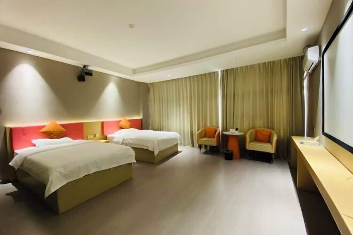A hotel room with two beds, a desk, a chair, and a large window with curtains.
