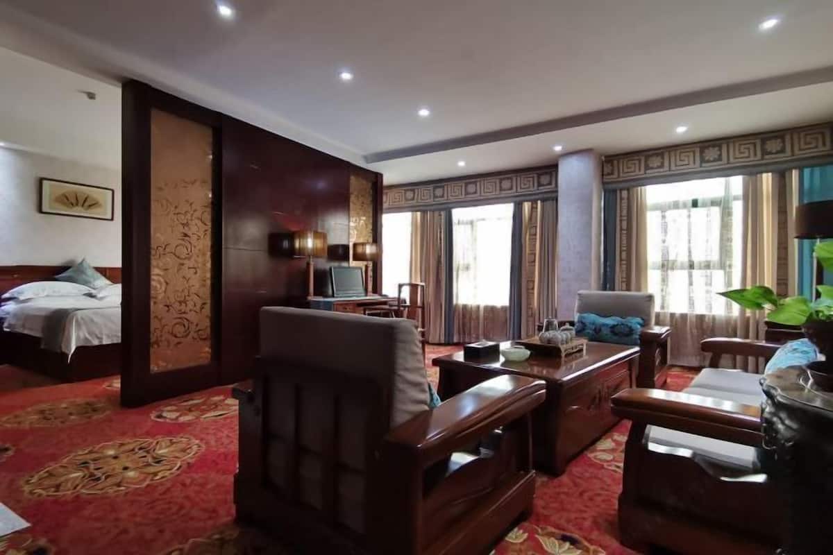 A hotel room with a bed, a desk, a chair, a television, and a large window with curtains.