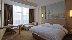 Une chambre d’hôtel avec un grand lit, un bureau avec une chaise, un canapé et un tableau au mur.