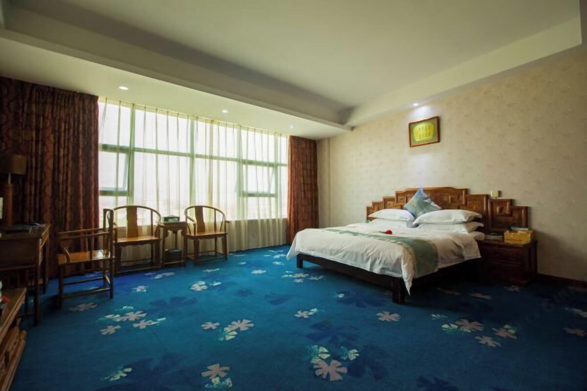 A bedroom with a bed, wooden nightstand, and a desk with chairs.