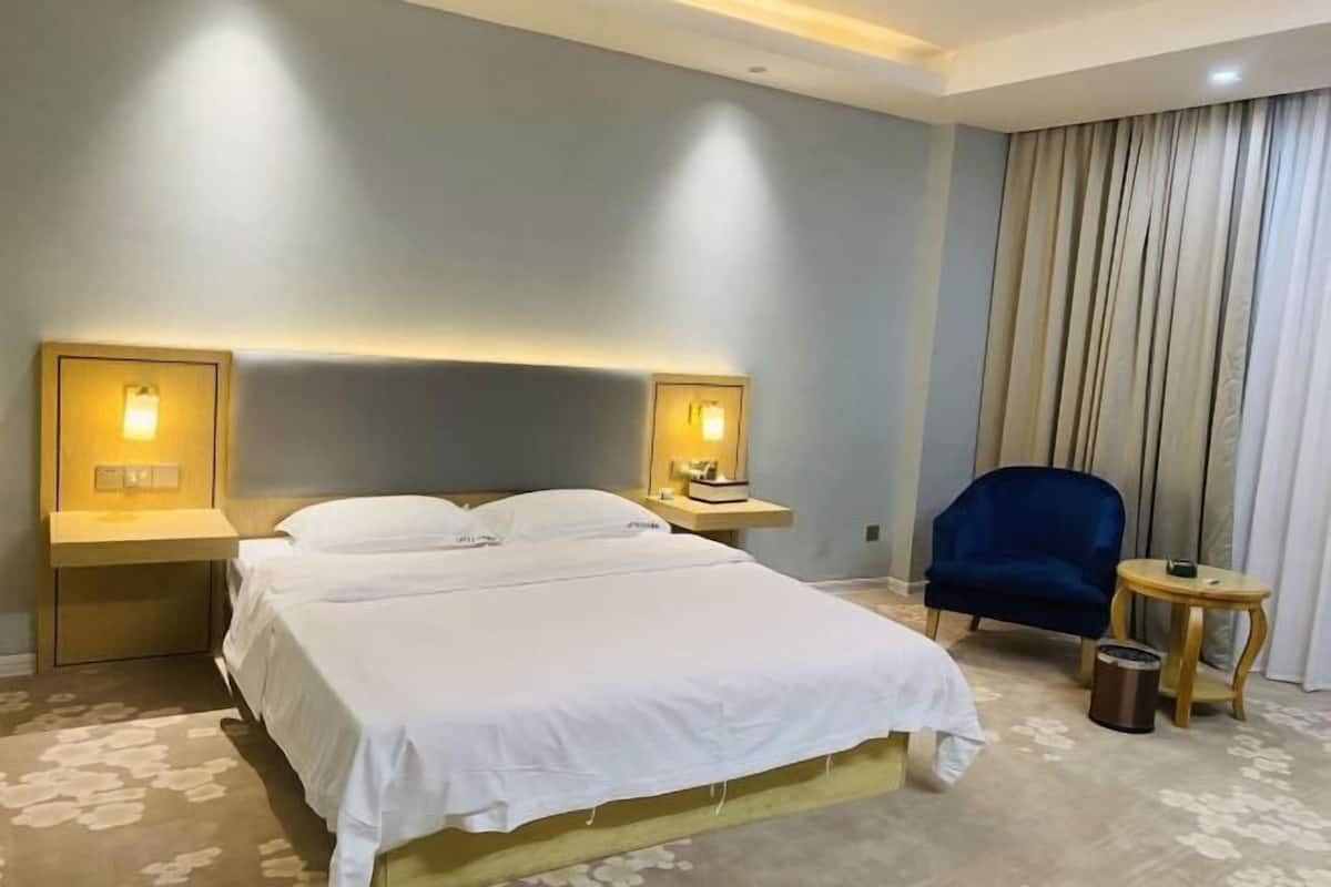 A hotel room with a bed, two bedside tables with lamps, a chair, and a small round table.